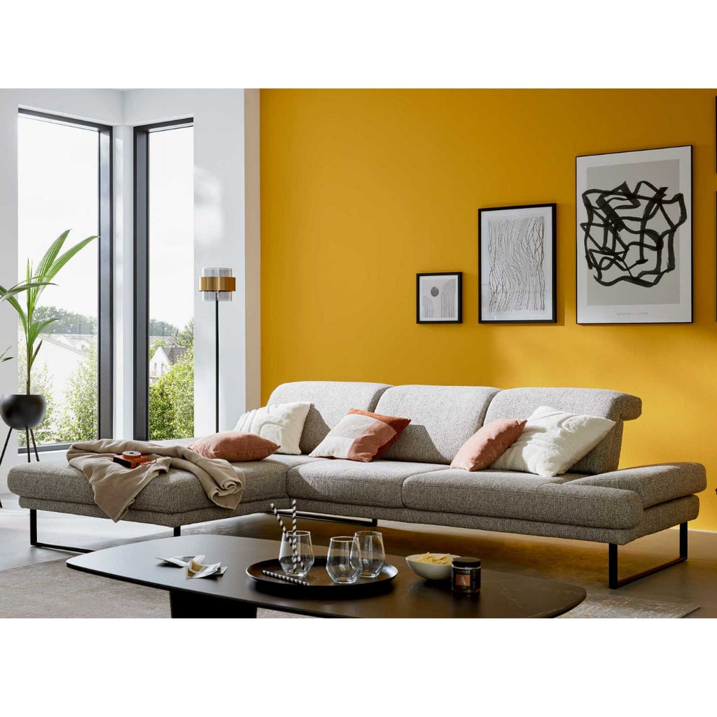 Modernes Wohnzimmer mit dem Ecksofa „Interliving 4460“ von Steinpol Polsteria IL in silbernem Stoff sowie einem schwarzen Couchtisch.