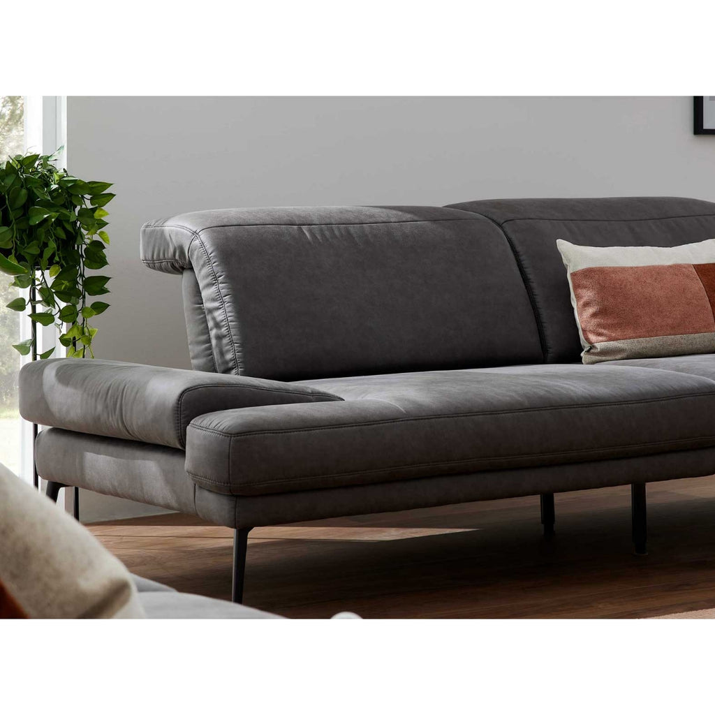 Steinpol Polsteria Zweisitzer-Sofa 4460, dunkelgrauer Stoff, schwarze Metallfüße, 2 Kissen, bei Fensterpflanze.