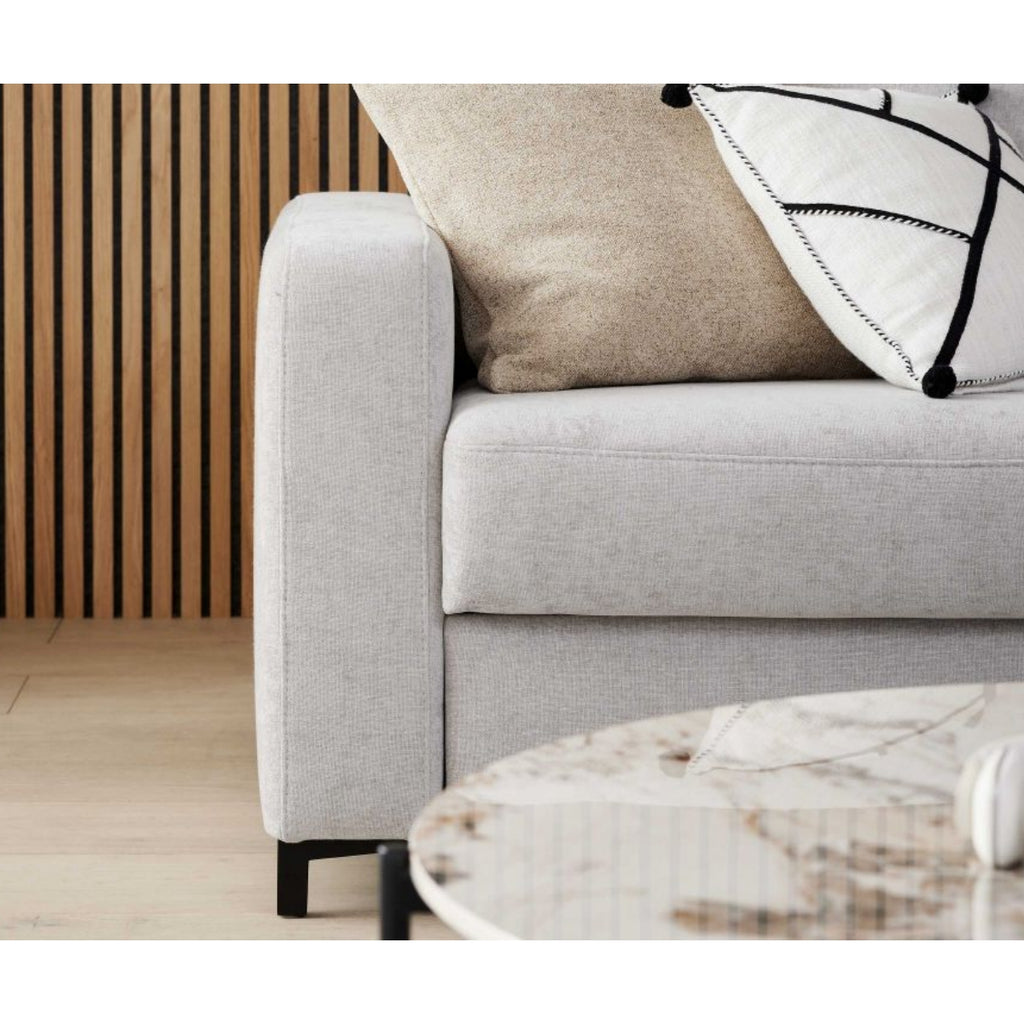 Toni Silver Interliving 4700 Eckkombination von HUKLA® Comfortbetten, daneben eine Wand aus Holzlatten und ein Couchtisch aus Marmor.