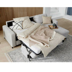 HUKLA® IL Interliving 4700 Eckkombination in der Farbe „Toni Silver“, mit beiger Bettwäsche, Kissen, Tablett und Snacks auf einem hellen Teppich.