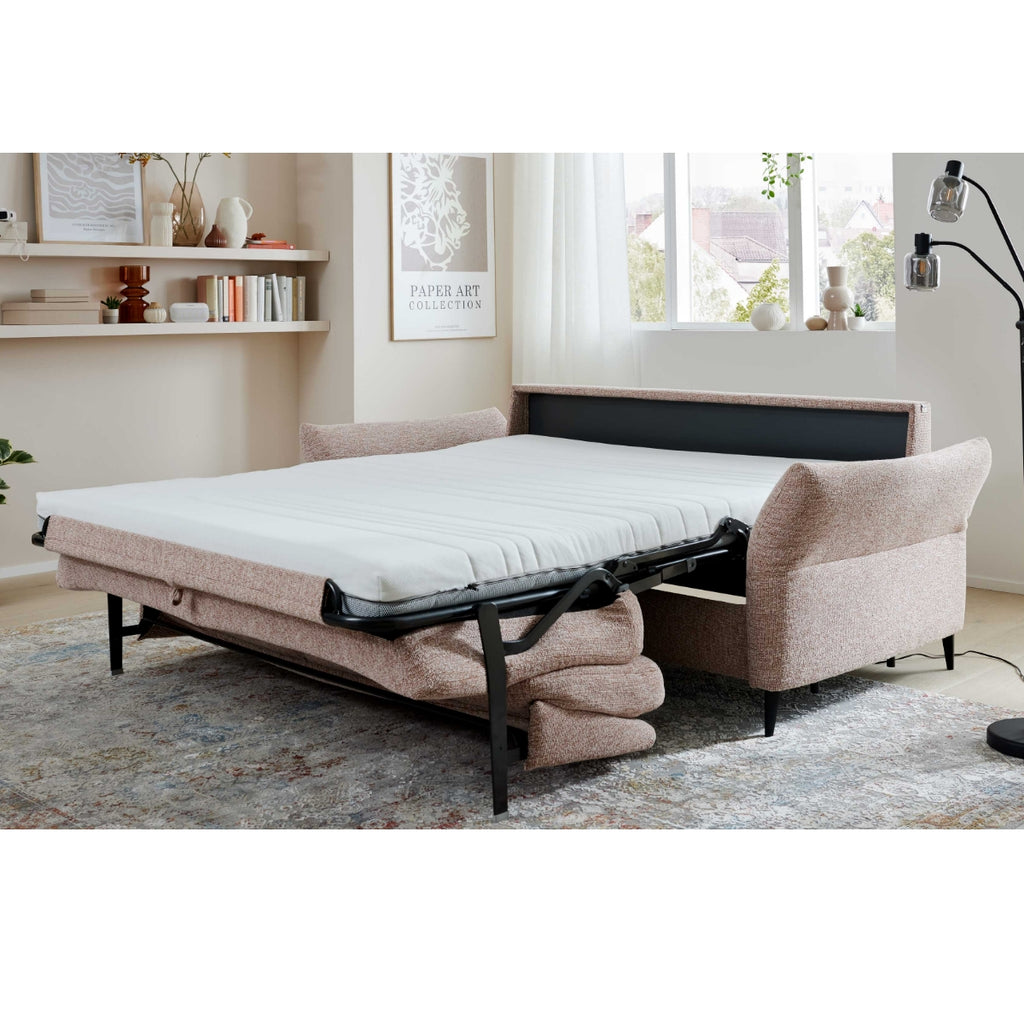 Ein Loft in Siena – HUKLA® Comfortbetten | Das Schlafsofa lässt sich ausklappen und gibt den Blick auf eine Matratze in einem modernen, hellen Wohnzimmer frei.