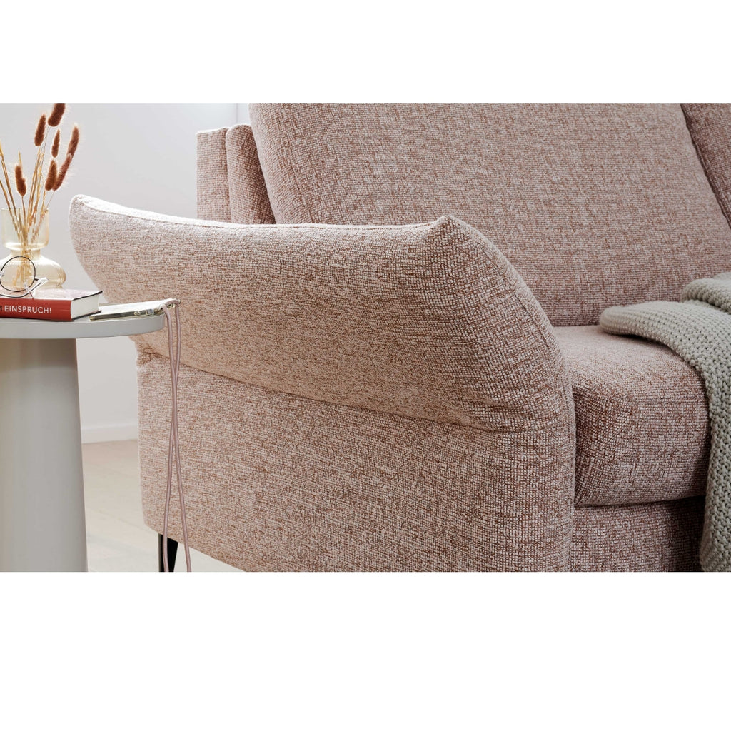 Beiges HUKLA®-Sofa der Serie 4700 in Längsausführung mit Struktur, daneben ein Tisch mit einem Buch, einer Vase und einer drapierten Strickdecke.