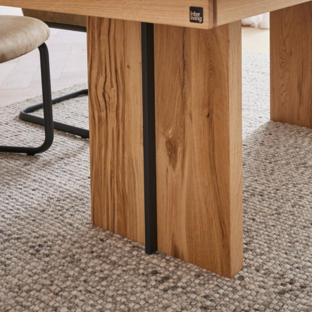 Nahaufnahme von VENJAKOB | IL Interliving 5604 Esstisch in natürlicher Optik, Tischbein auf strukturiertem grauen Teppich.