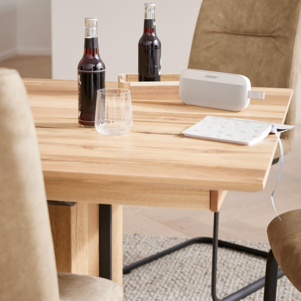 Limonadenflaschen, ein Glas und ein Bose-Lautsprecher auf dem VENJAKOB | IL Interliving 5604 Esstisch in natürlicher Optik.