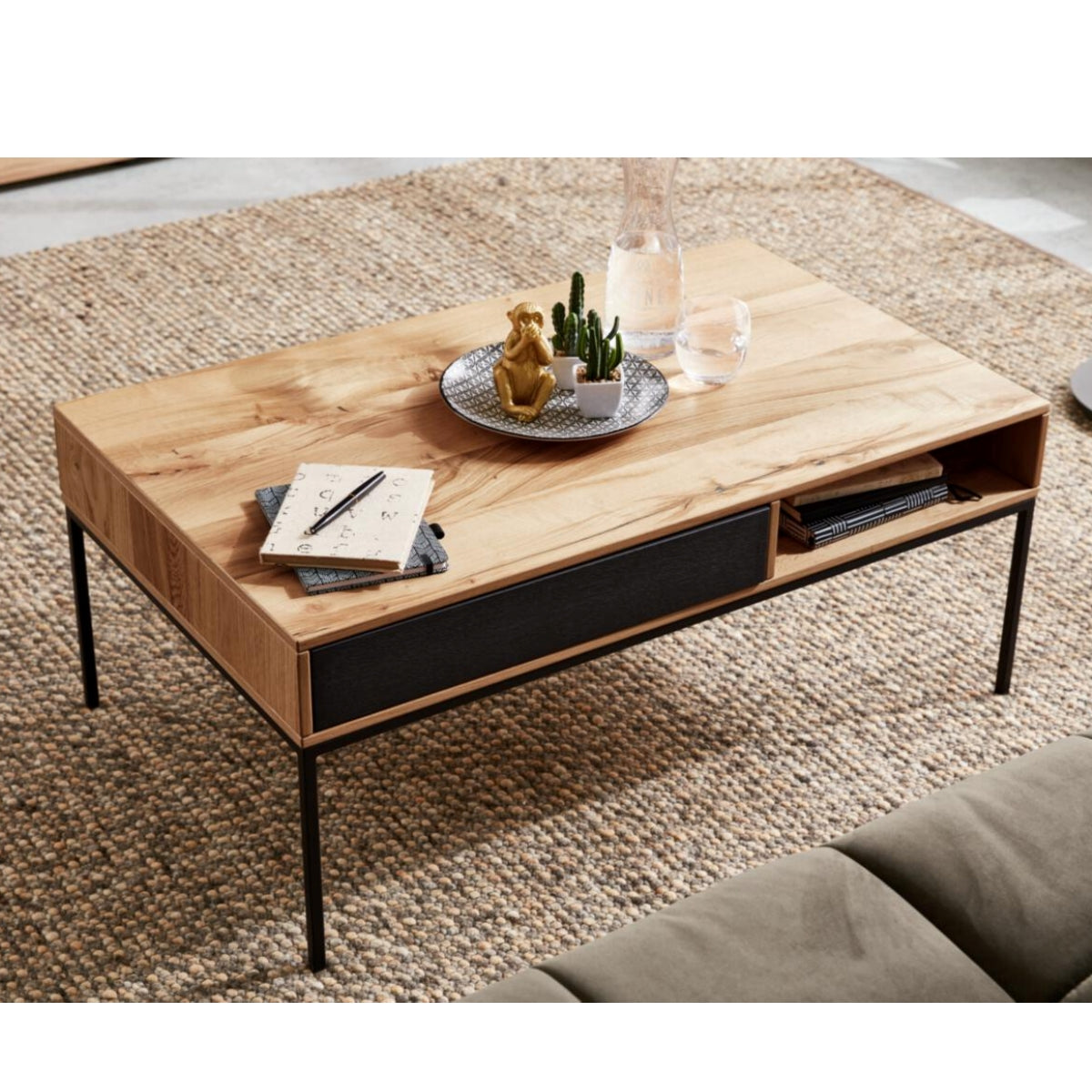 Couchtisch „Interliving Serie 5604“ von VENJAKOB | IL aus heller Rustico-Eiche, mit mattanthrazitfarbenen Metallbeinen, auf einem gewebten Teppich.