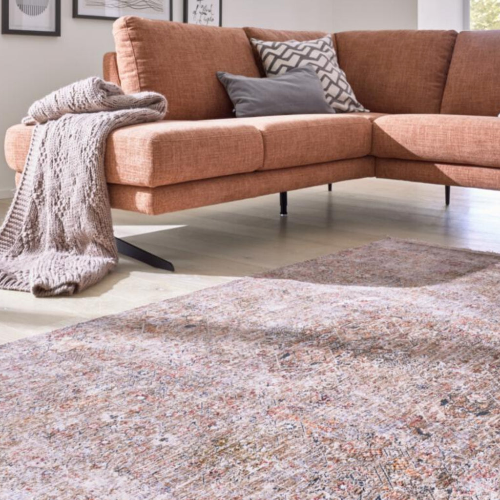 Orangefarbenes L-förmiges Sofa mit grauen Kissen, einer Strickdecke und einem Vintage-Teppich von GOLZE | IL Interliving G-8070 auf einem Holzboden.