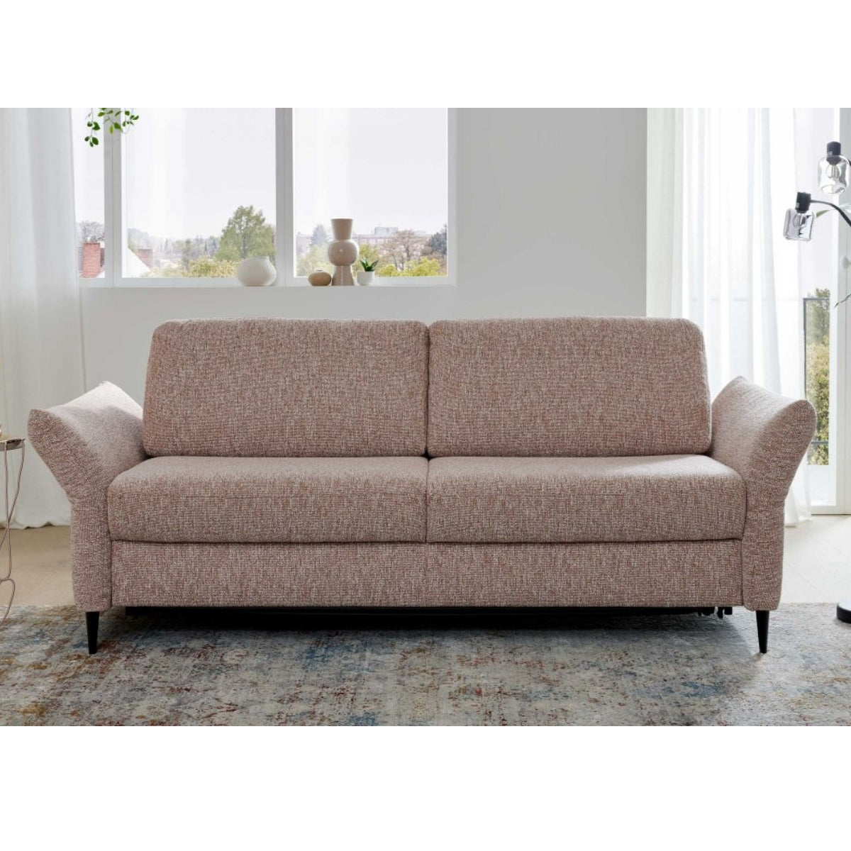 HUKLA® Interliving Serie 4700 Längsschläfer, Loft Siena, abgewinkelte Armlehnen, in Fensternähe auf einem gemusterten Teppich.