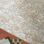 Nahaufnahme von GOLZE | IL Interliving G-8040: fein gemusterter Teppich in Beige/Creme, dezenter Vintage-Look; Tisch im Vordergrund.