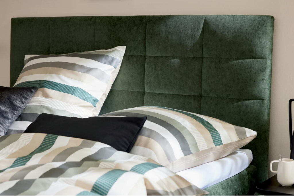 Boxspringbett mit moosgrünem Bezug und schwarzen Metallfüßen