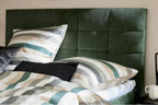 Boxspringbett mit moosgrünem Bezug und schwarzen Metallfüßen