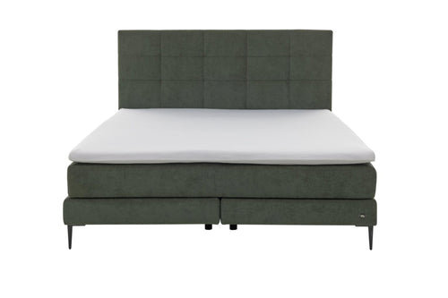 Boxspringbett mit moosgrünem Bezug und schwarzen Metallfüßen