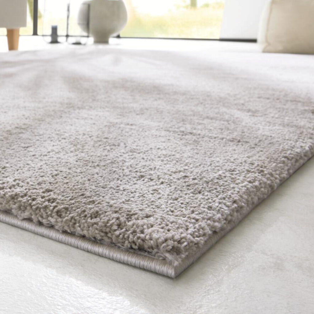 Nahaufnahme des GOLZE | IL Hochflor-Teppichs in elegantem Hellgrau mit weicher Haptik auf einem hellen Boden.