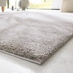 Nahaufnahme des GOLZE | IL Hochflor-Teppichs in elegantem Hellgrau mit weicher Haptik auf einem hellen Boden.