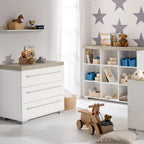Ein fröhliches Kinderzimmer mit Sternentapete, Regalen und einem Kleiderschrank „0190 PAIDI Kira“ für ordentliche Aufbewahrung.