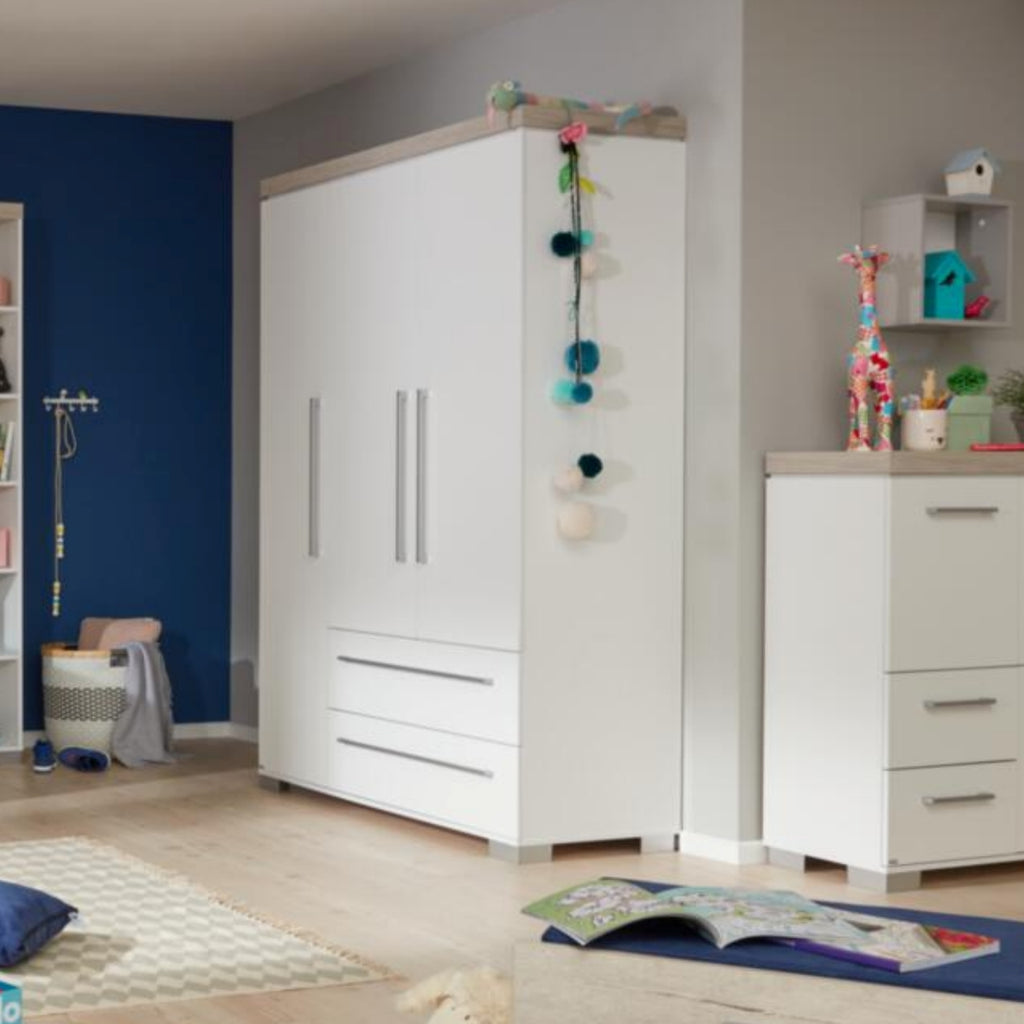 Der PAIDI Kira Kleiderschrank in Kreideweiß steht neben einer Kommode in einem modernen, aufgeräumten Kinderzimmer.