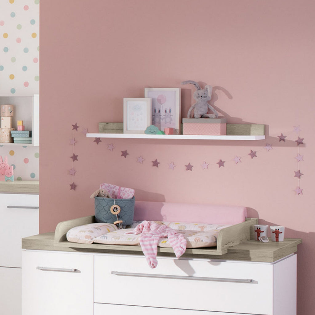 PAIDI Kira Kinderzimmer mit Wandregal in Kreideweiß/Eiche für Spielzeug, Deko, Kunstwerke und einer Sternengirlande über dem Wickeltisch.