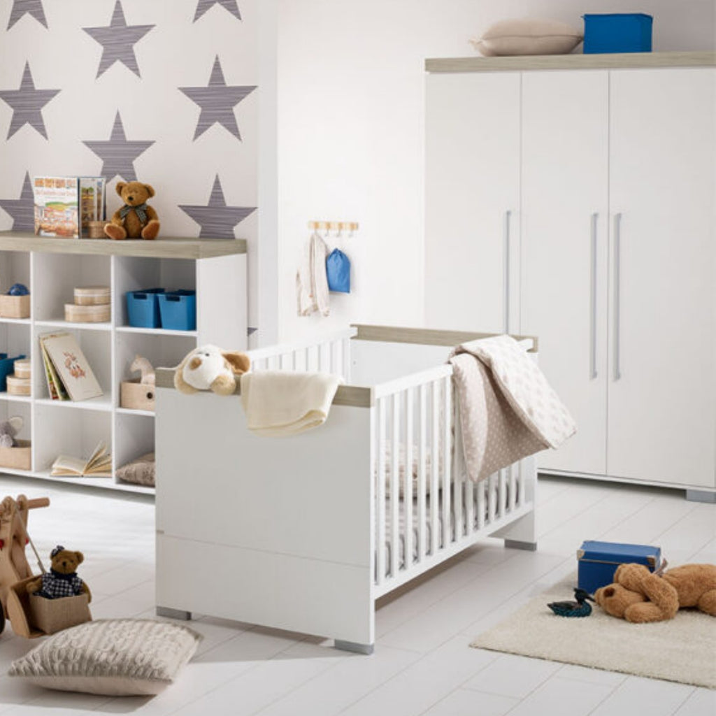 Modernes Kinderzimmer mit weißem Kinderbett, Sternentapete, Regalen mit Spielzeug und dem PAIDI 0190 Kira Kleiderschrank im 3T-Design.
