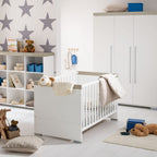 Modernes Kinderzimmer mit weißem Kinderbett, Sternentapete, Regalen mit Spielzeug und dem PAIDI 0190 Kira Kleiderschrank im 3T-Design.