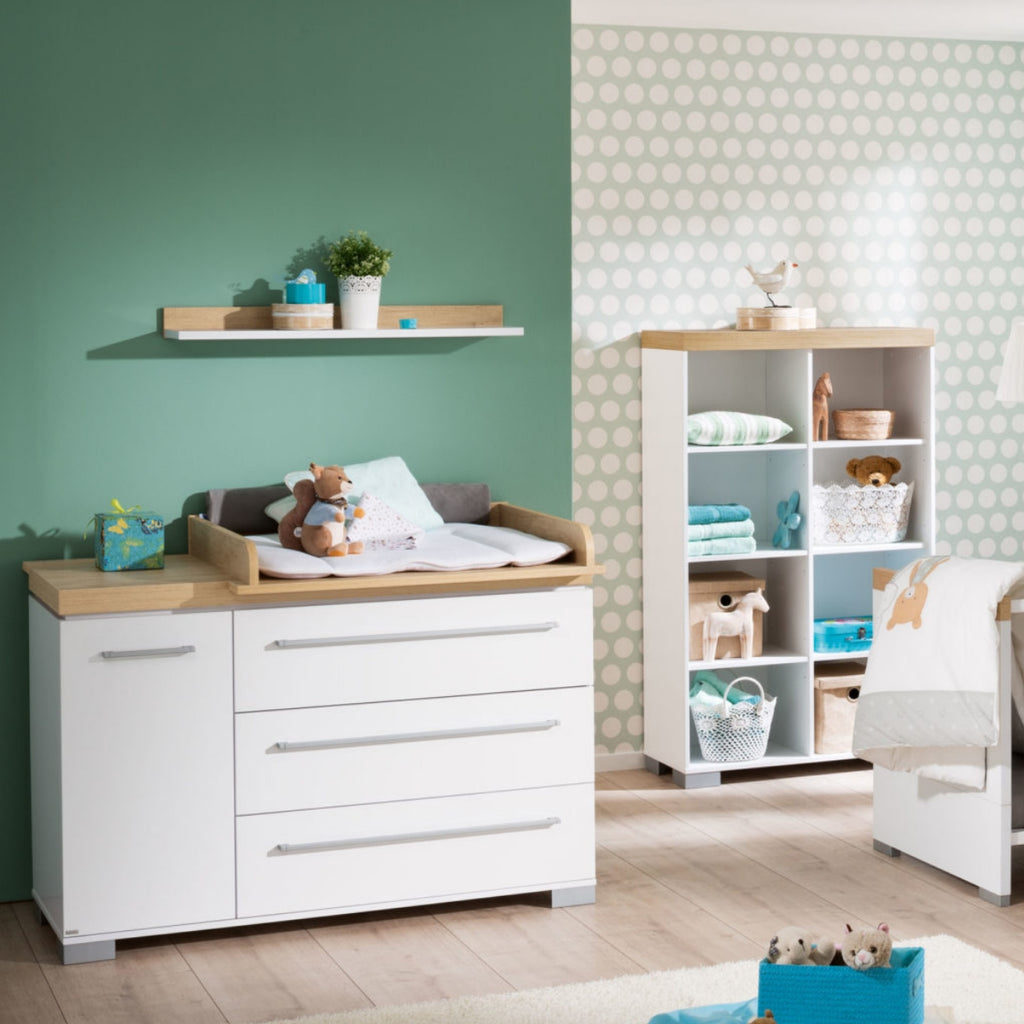 Modernes Babyzimmer mit grün gepunkteten Wänden, einer PAIDI Kira Kommode von 0190, Regalen und ordentlich sortiertem Spielzeug.