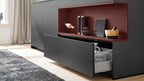 Die elegante WERT KÜCHE® Nora von Schüller: schwarzes Design, rote Akzente, offene Schublade und Einbaugeräte von Siemens für einen modernen Look.