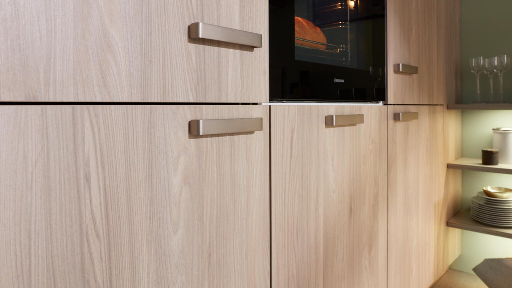 WERT KÜCHE® Mona: Helle Küchenschränke im nordischen Stil, silberne Griffe, Constructa-Backofen und offene Regale auf der rechten Seite.