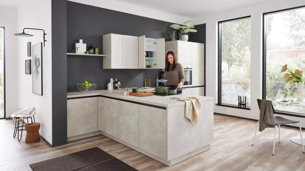 Eine Frau beim Kochen in der WERT KÜCHE® Ella: Modernes Design mit klaren Linien, hellen Farbtönen und markanten Akzenten.