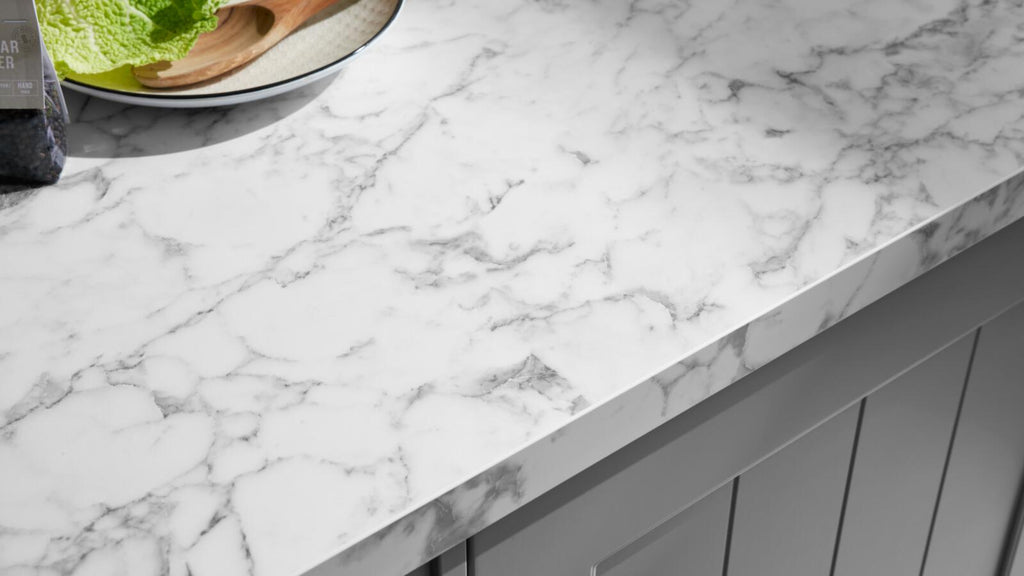 WERT KÜCHE® Carina in Achatgrau mit weißer Marmorplatte, seidenmatten Fronten und einer Salatplatte neben dem grauen Schrank.