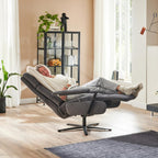 Jemand entspannt sich in einem „OrthoSedis 4.0 Relaxsessel L3“ von Steinpol Polsteria in einem hellen Wohnzimmer mit Pflanzen und einer Vitrine.