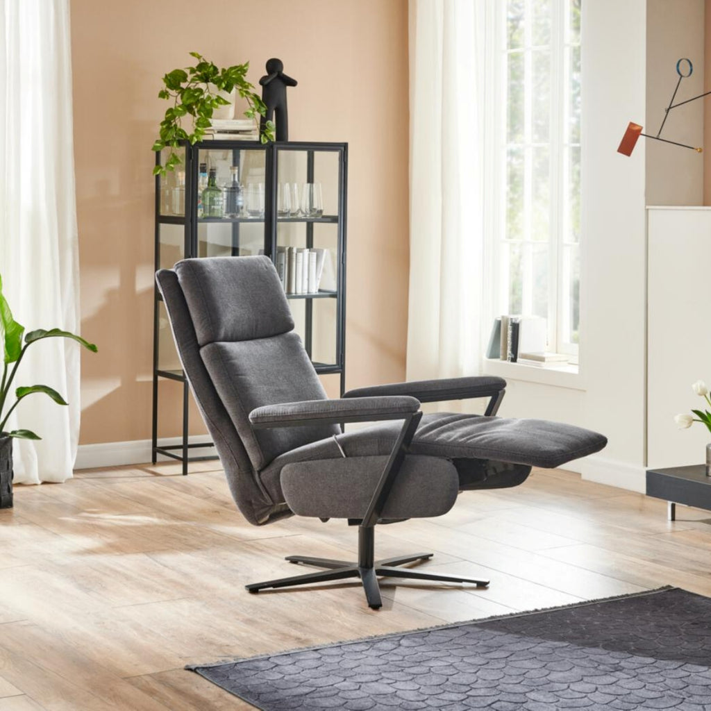 Der Relaxsessel „OrthoSedis 4.0 L3“ von Steinpol Polsteria in einem modernen Raum mit Pflanzen, einer Vitrine und einem sonnigen Fenster.