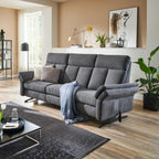 Modernes Wohnzimmer mit dem Rundsofa „OrthoSedis 4.0“ von Steinpol Polsteria, einer blauen Decke, Pflanzen, Kunstwerken und einem Couchtisch auf einem Teppich.