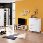 Modernes Wohnzimmer mit gelber Akzentwand, PAIDI Oscar Lowboard, weißem Schrank und geometrischen Teppichen.