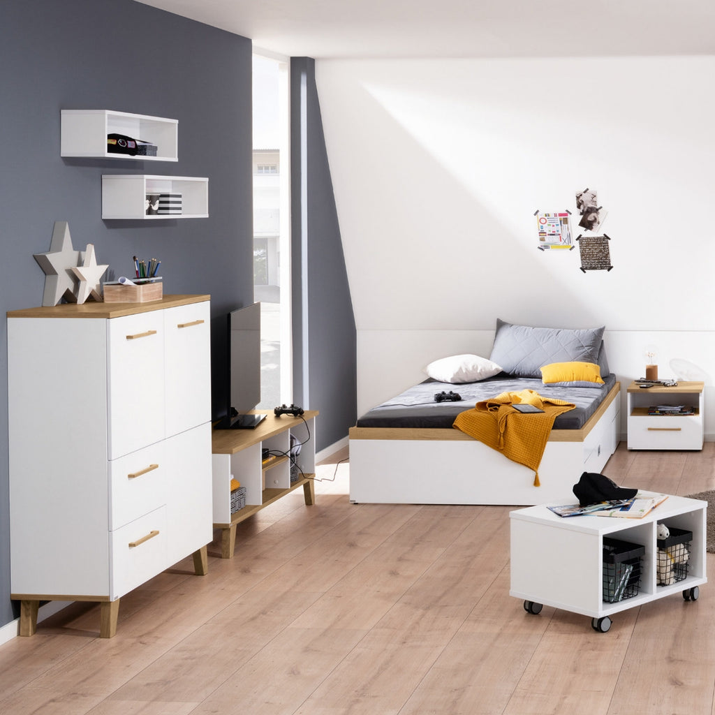 Modernes Schlafzimmer mit dem PAIDI Oscar-Hochschrank, weißen Möbeln in Nebraska-Eiche-Optik und Sonnenlicht, das durch das Fenster fällt.