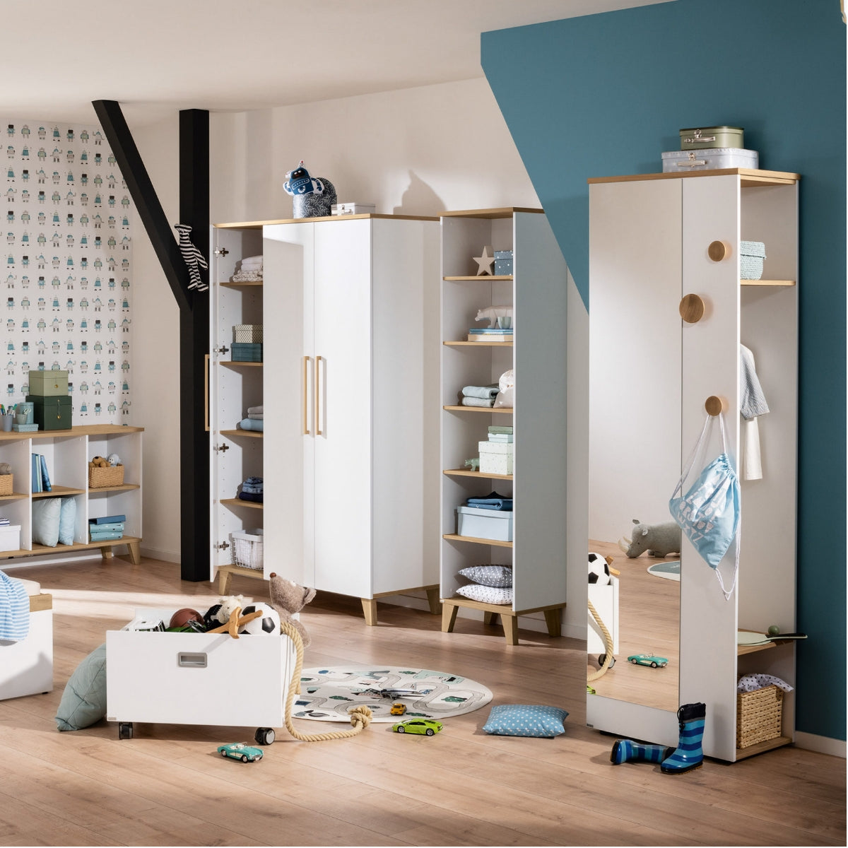 Modernes Kinderzimmer mit dem Kleiderschrank „PAIDI Oscar 135 670 4“, Spielzeug, Regalen aus Melamin und blau-weißen Wänden.