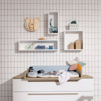 Kinderzimmer mit der Wandbox „Oscar“ aus dem PAIDI-Jugendzimmerprogramm, Babyausstattung, Spielzeug, Ablagefach und einem Holzbären an der Gitterwand.