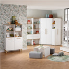 Kinderzimmer mit weißem PAIDI Oscar-Eckschrank, Spielzeug, Spielecke und einer Wand mit Blattmuster.