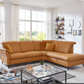 Wohnzimmer mit einem Ecksofa des Systems „Polsteria Senturo“ von Steinpol in senfgelbem Leder, großen Fenstern und stilvollen Wandregalen.