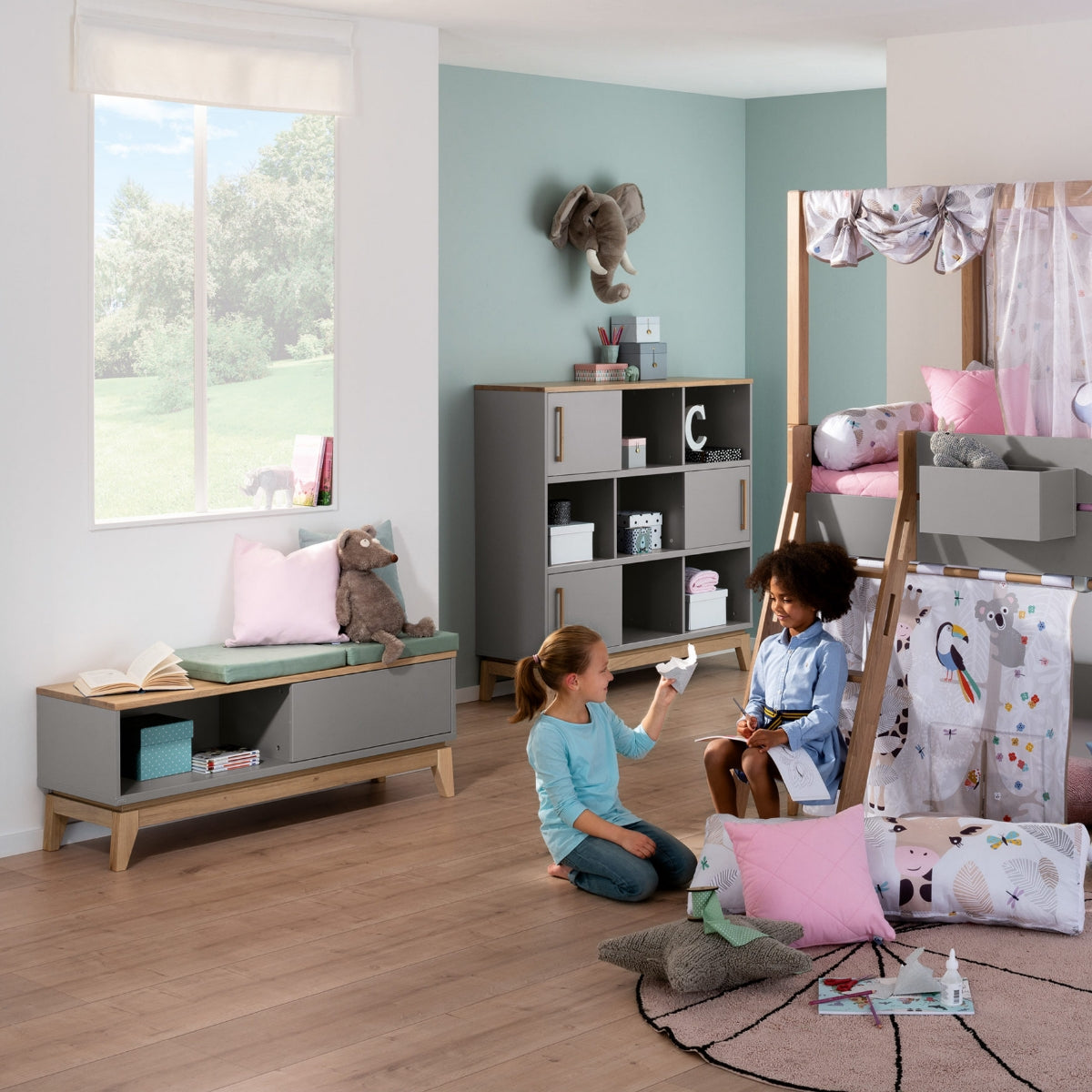 Zwei Kinder spielen in einem modernen Kinderzimmer mit Spielzeug, Etagenbetten und dem PAIDI Jugendzimmer Lowboard Sten von PAIDI.