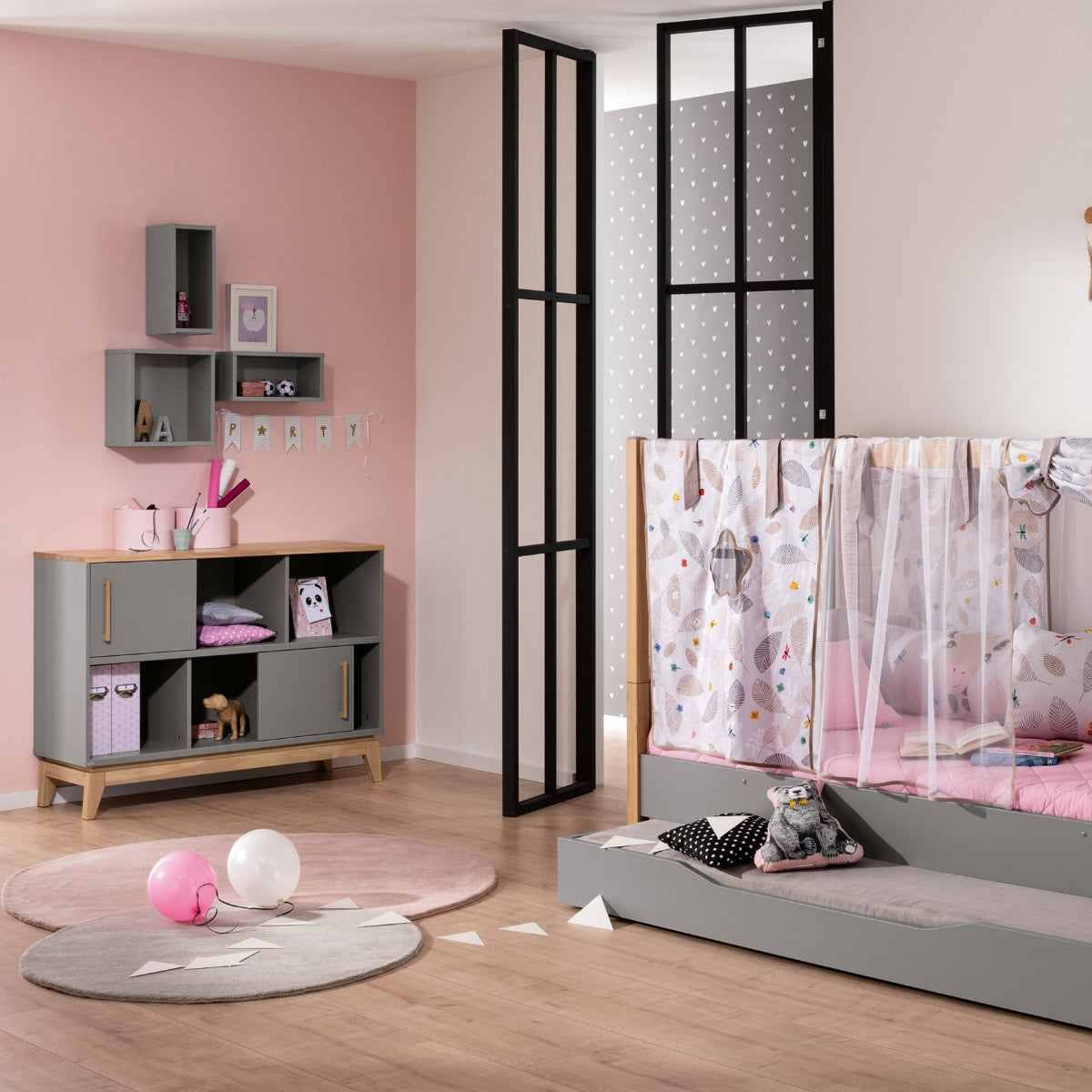 Modernes Kinderzimmer in Rosa und Grau, in dem das PAIDI Sideboard „Sten“ in Schiefergrau und massiver Eiche besonders zur Geltung kommt.