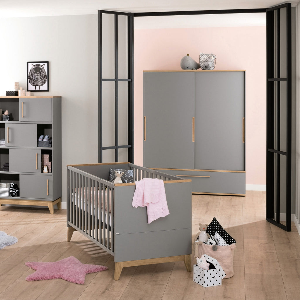Modernes Kinderzimmer mit dem PAIDI Babyzimmer Sten – Babybettgestell, Holzboden, pastellfarbenen Akzenten und zartrosa Dekoration.