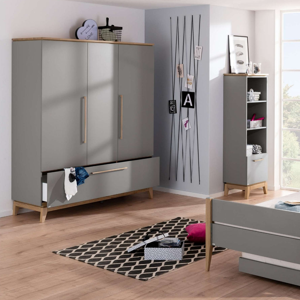 Modernes graues Schlafzimmer mit einem PAIDI-Kleiderschrank „Sten“, Regalen, einem Bett, einem Teppich und Fotos an der sonnendurchfluteten Wand am Fenster.