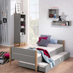 Modernes Schlafzimmer mit schiefergrauen Melaminoberflächen, dem PAIDI-Ständerregal „Sten“ für das Babyzimmer, einer Wand mit Polka-Dots und Pastelltönen.