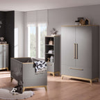 Modernes Kinderzimmer mit einem PAIDI-Kleiderschrank „Sten“, einem Kinderbett, Regalen und Sonnenlicht, das durch das Fenster hereinströmt.