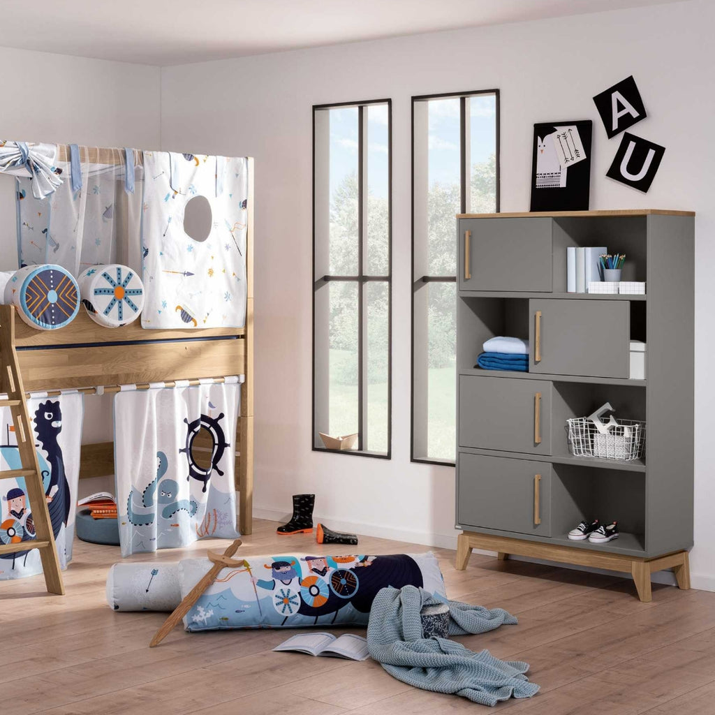 Kinderzimmer mit einem Etagenbett, verspielter Einrichtung und einem PAIDI-Stauraumelement „Sten“ neben hohen Fenstern.