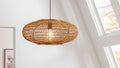 Pendelleuchte aus geflochtenem Rattan in ovaler Form mit sichtbarem Edison-Glühbirnen-Einsatz, aufgehängt an einer schwarzen Schnur.
