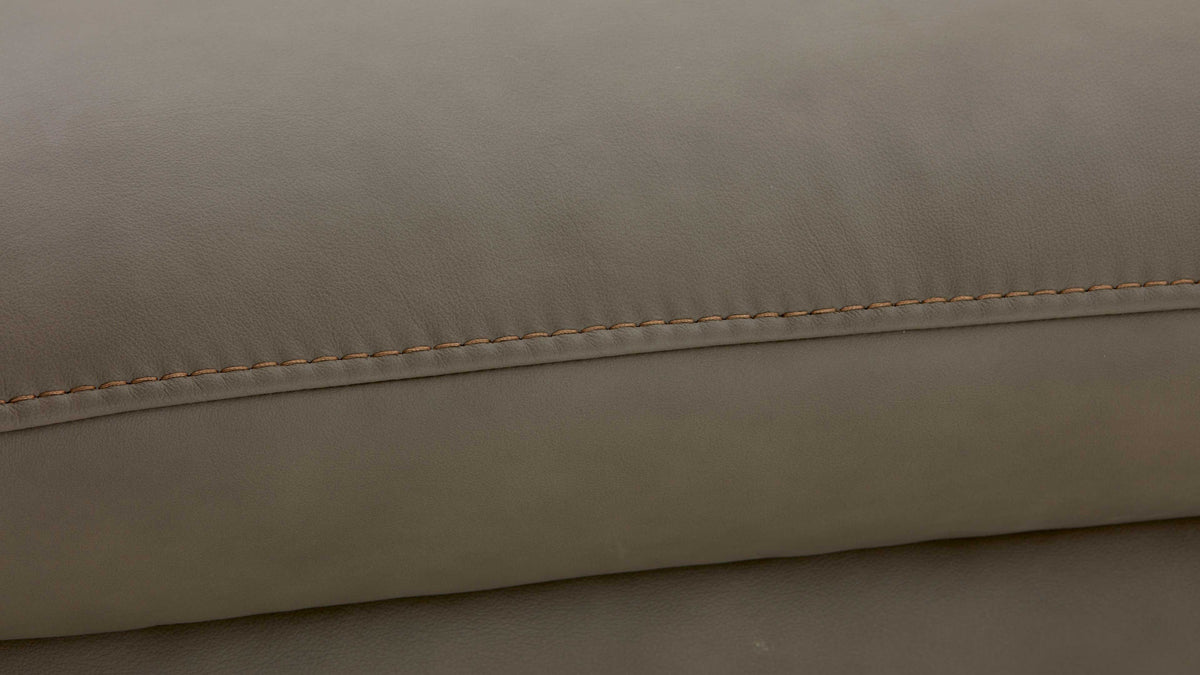 Nahaufnahme eines grauen, ledengerpolsterten Möbelstücks mit sichtbarer Naht und einem dezenteren, klaren Design.