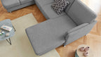 Beige Teppichboden unter einer grauen, L-förmigen Couch mit einem gemusterten Kissen, neben einem Couchtisch mit Dekoartikeln.