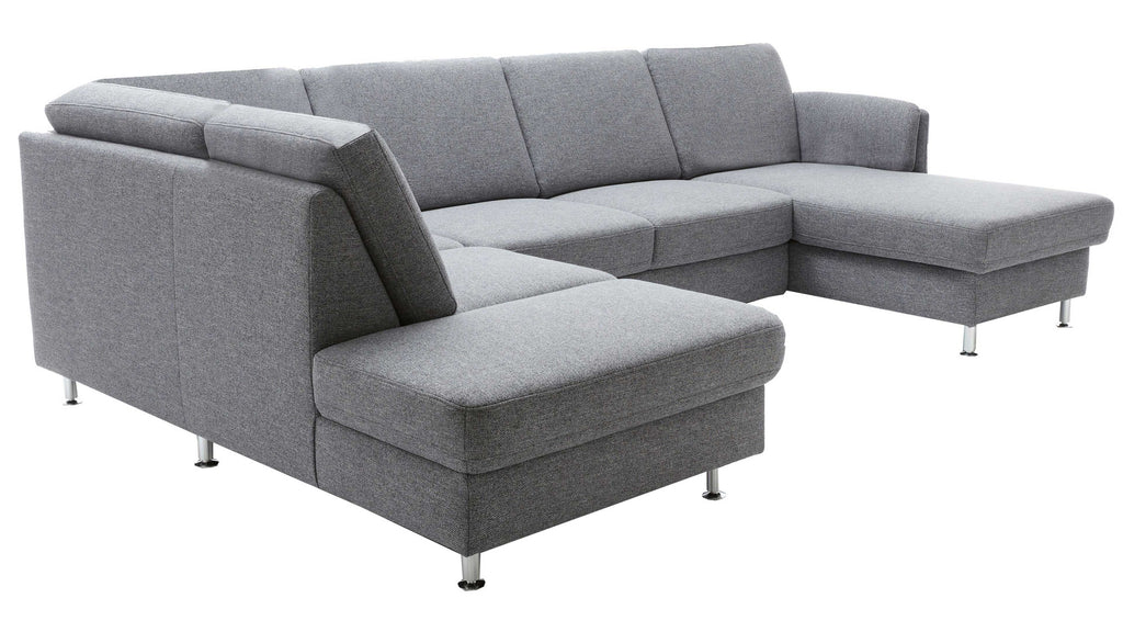 Ecksofa in hellgrauem Stoff mit Metallfüßen, bestehend aus einer langgestreckten Sitzfläche, Rückenlehne und einer gepolsterten Anlehne.