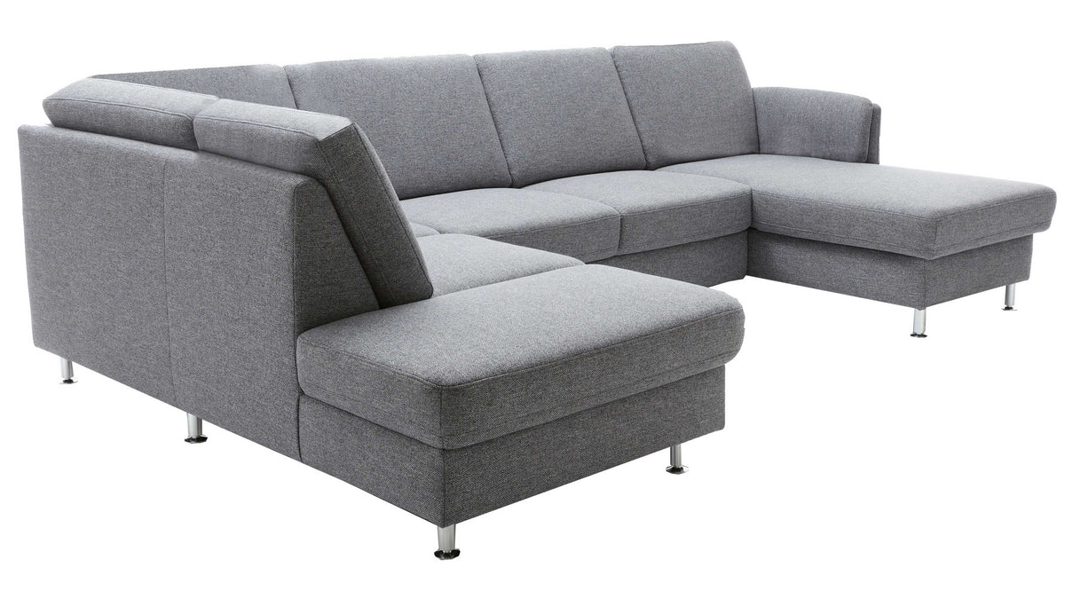 Ecksofa in hellgrauem Stoff mit Metallfüßen, bestehend aus einer langgestreckten Sitzfläche, Rückenlehne und einer gepolsterten Anlehne.