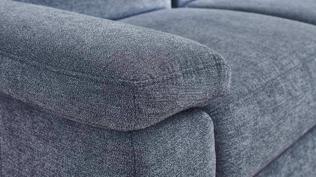 Die Ausgestaltung der Kante einer blauen Couch mit einer weichen, strukturierten Polsterung ist sichtbar.