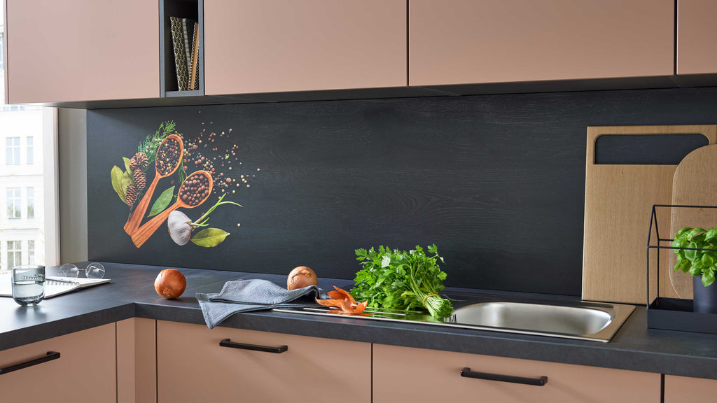 In einer modernen Küche sind ein Edelstahlspülbecken, frische Kräuter, Gemüse, ein Holzbrett und eine dekorative Wandgestaltung mit Gewürzen sichtbar.